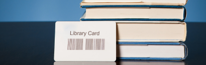 library card sitting in front of a stack of books on a dark background