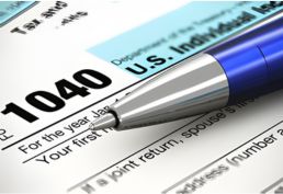 close up of a 1040 tax form with a blue pen sitting on top