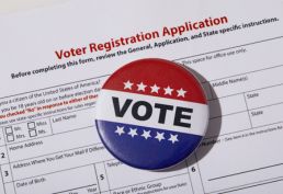 red, white, blue vote button son top of a voter registration form
